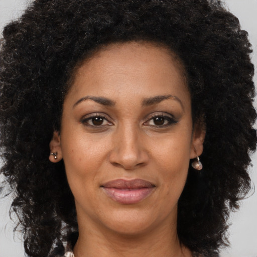 Joyful black young-adult female with long  brown hair and brown eyes