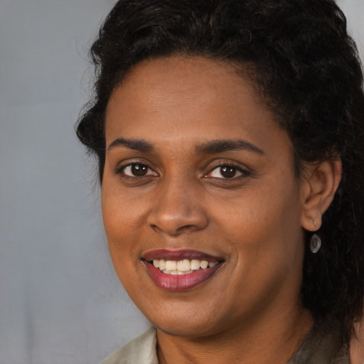 Joyful black adult female with long  brown hair and brown eyes