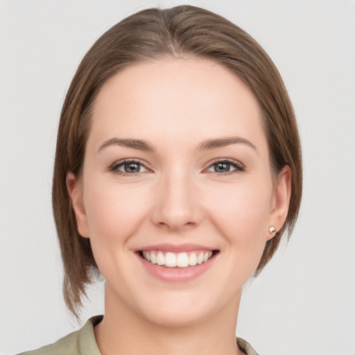 Joyful white young-adult female with medium  brown hair and grey eyes