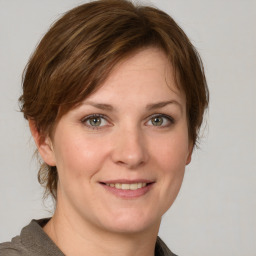 Joyful white young-adult female with medium  brown hair and grey eyes