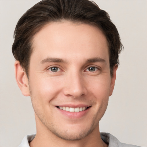 Joyful white young-adult male with short  brown hair and grey eyes