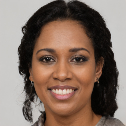 Joyful black young-adult female with long  brown hair and brown eyes