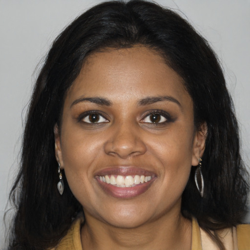 Joyful black young-adult female with long  brown hair and brown eyes