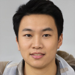 Joyful asian young-adult male with short  black hair and brown eyes