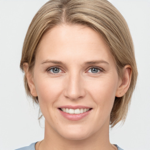 Joyful white young-adult female with medium  brown hair and grey eyes