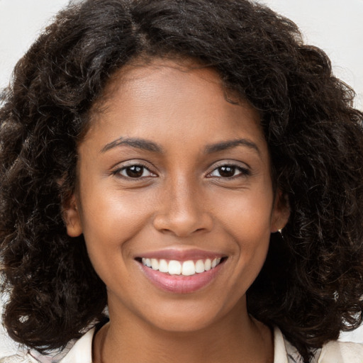 Joyful black young-adult female with long  brown hair and brown eyes