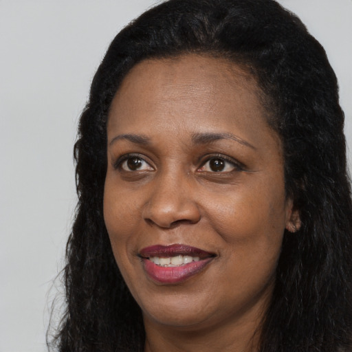 Joyful black adult female with long  black hair and brown eyes