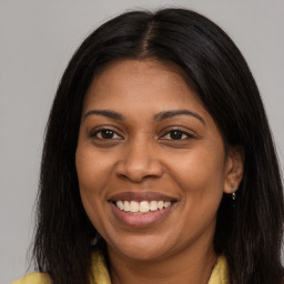 Joyful black young-adult female with long  brown hair and brown eyes