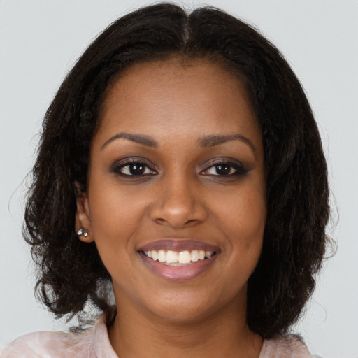 Joyful black young-adult female with long  brown hair and brown eyes