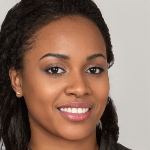 Joyful black young-adult female with long  brown hair and brown eyes