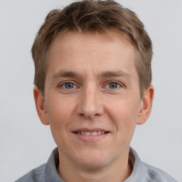 Joyful white young-adult male with short  brown hair and grey eyes