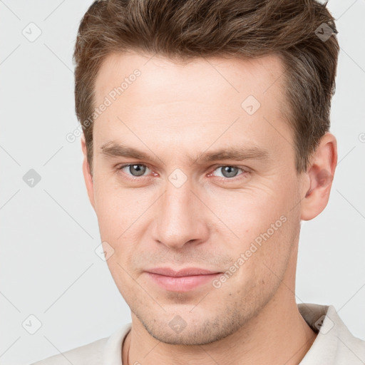 Joyful white young-adult male with short  brown hair and grey eyes