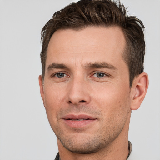 Joyful white young-adult male with short  brown hair and grey eyes