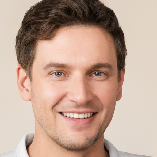 Joyful white young-adult male with short  brown hair and grey eyes