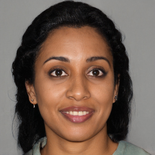 Joyful black young-adult female with long  black hair and brown eyes