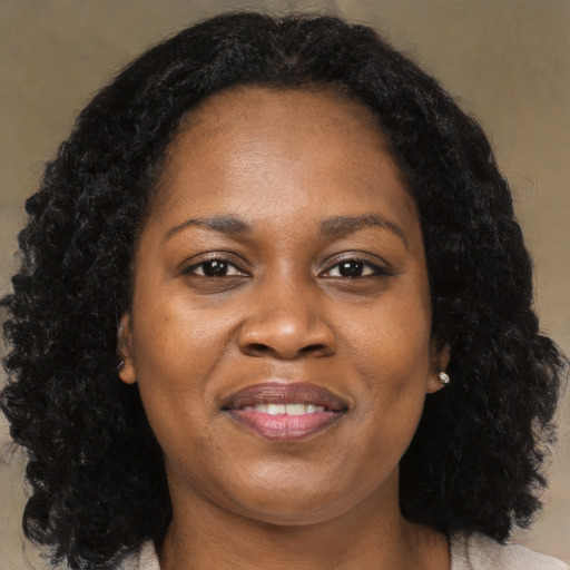 Joyful black adult female with long  brown hair and brown eyes