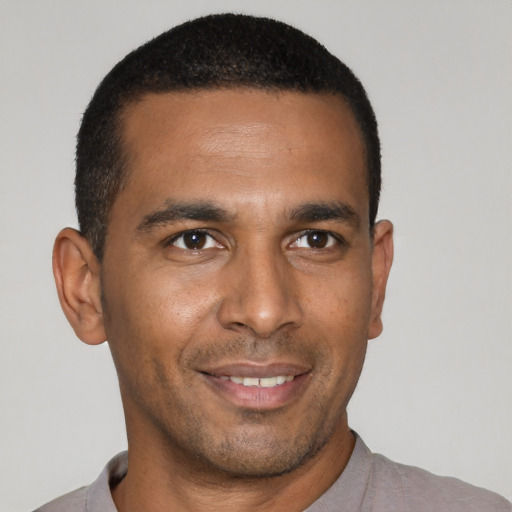 Joyful black young-adult male with short  brown hair and brown eyes