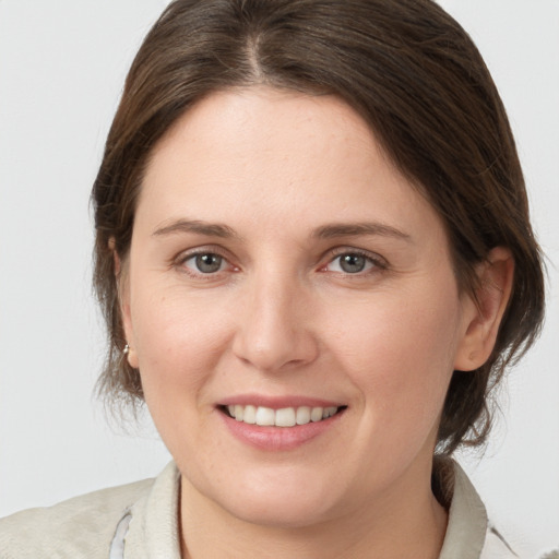 Joyful white young-adult female with medium  brown hair and grey eyes