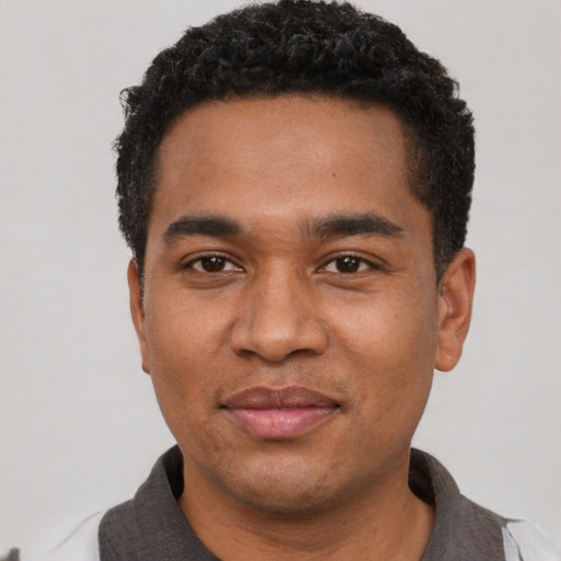 Joyful black young-adult male with short  black hair and brown eyes