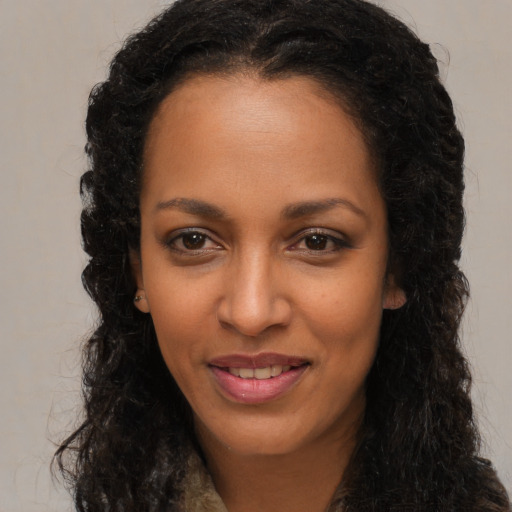 Joyful black young-adult female with long  brown hair and brown eyes