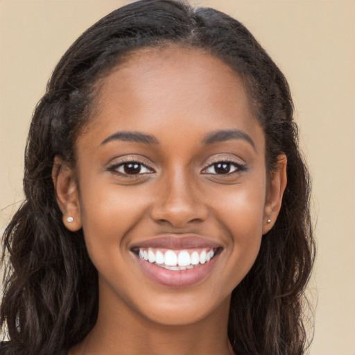 Joyful black young-adult female with long  brown hair and brown eyes