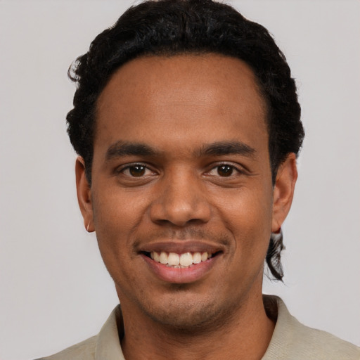 Joyful black young-adult male with short  black hair and brown eyes