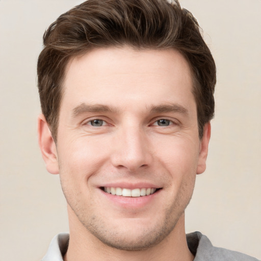 Joyful white young-adult male with short  brown hair and grey eyes