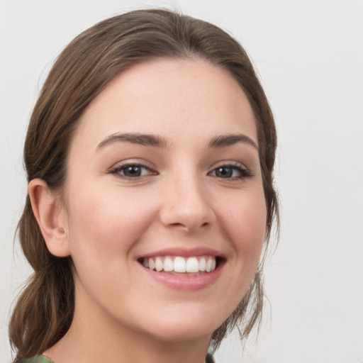 Joyful white young-adult female with medium  brown hair and grey eyes