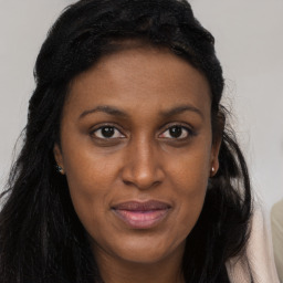 Joyful black young-adult female with long  brown hair and brown eyes