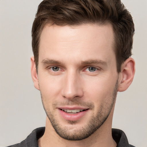 Joyful white young-adult male with short  brown hair and grey eyes