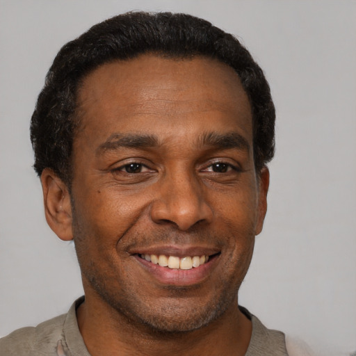 Joyful black adult male with short  black hair and brown eyes