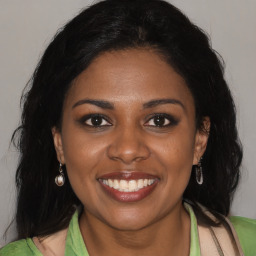 Joyful black young-adult female with long  brown hair and brown eyes