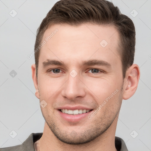 Joyful white young-adult male with short  brown hair and grey eyes