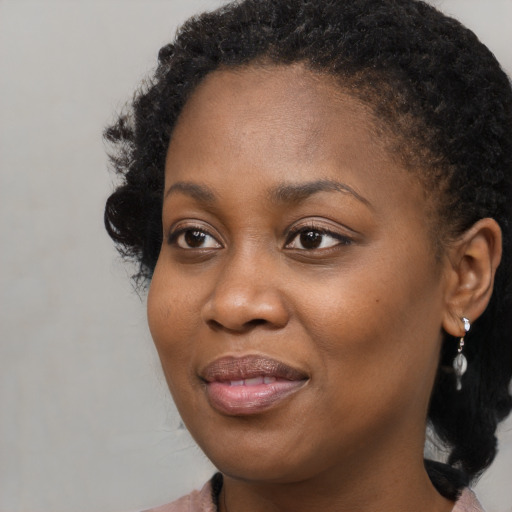 Joyful black young-adult female with long  black hair and brown eyes