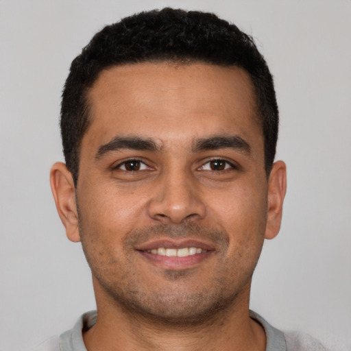 Joyful latino young-adult male with short  brown hair and brown eyes