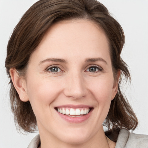 Joyful white young-adult female with medium  brown hair and grey eyes