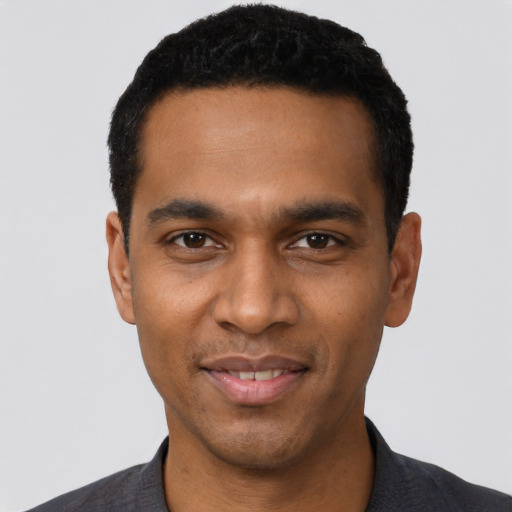 Joyful black young-adult male with short  black hair and brown eyes