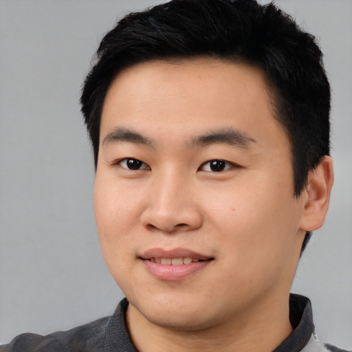 Joyful asian young-adult male with short  black hair and brown eyes