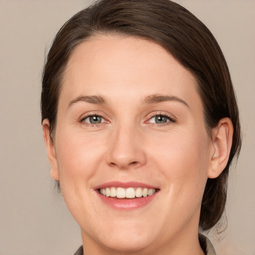 Joyful white young-adult female with medium  brown hair and grey eyes