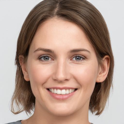 Joyful white young-adult female with medium  brown hair and grey eyes