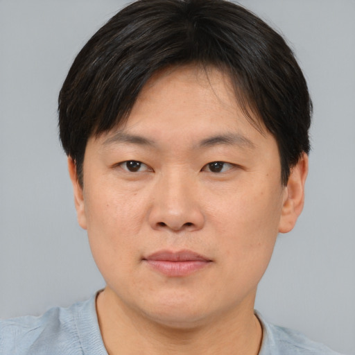 Joyful asian young-adult male with short  brown hair and brown eyes