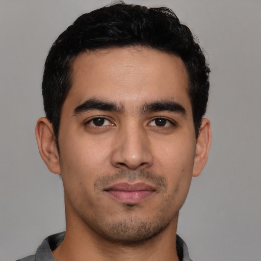 Joyful latino young-adult male with short  black hair and brown eyes