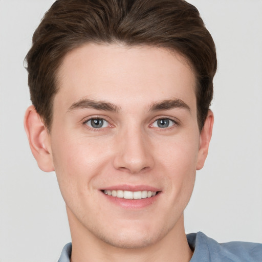 Joyful white young-adult male with short  brown hair and grey eyes