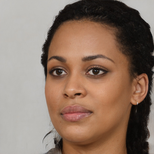 Joyful black young-adult female with long  black hair and brown eyes