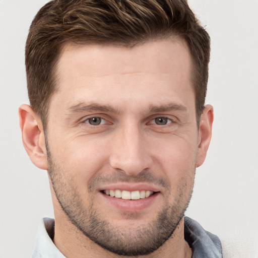 Joyful white young-adult male with short  brown hair and grey eyes