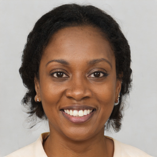 Joyful black young-adult female with long  brown hair and brown eyes