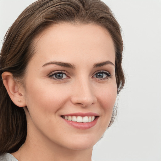 Joyful white young-adult female with medium  brown hair and grey eyes