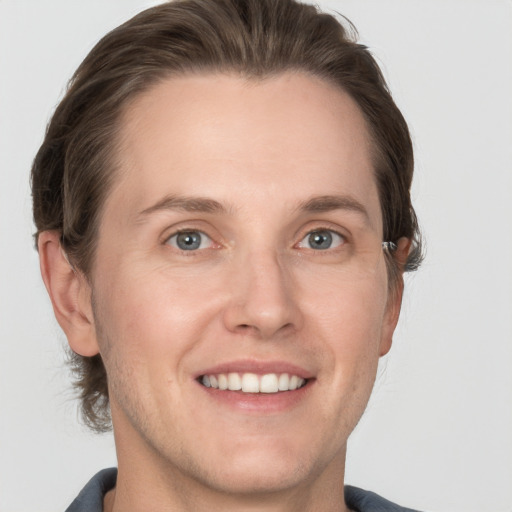 Joyful white young-adult male with medium  brown hair and grey eyes