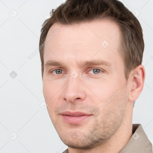 Joyful white young-adult male with short  brown hair and grey eyes