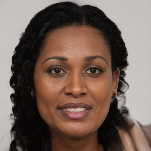 Joyful black young-adult female with long  brown hair and brown eyes
